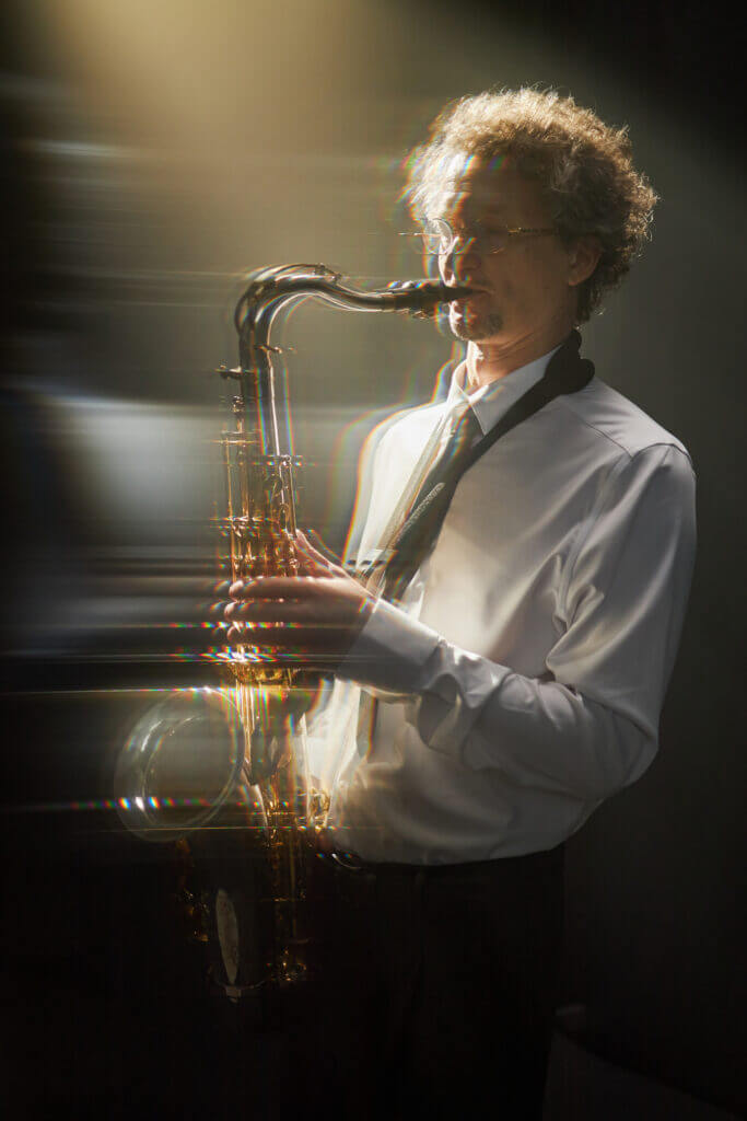 Ein Mann spielt Saxophon im Sonnenschein, Licht strahlt auf das Instrument.