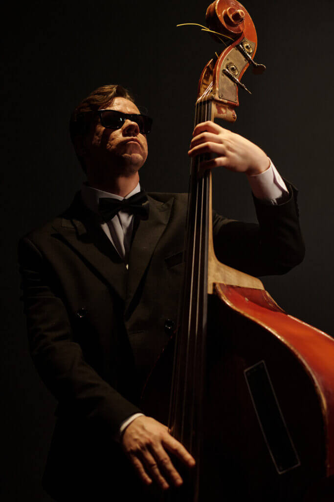 Musiker in Anzug mit Sonnenbrille spielt Kontrabass.